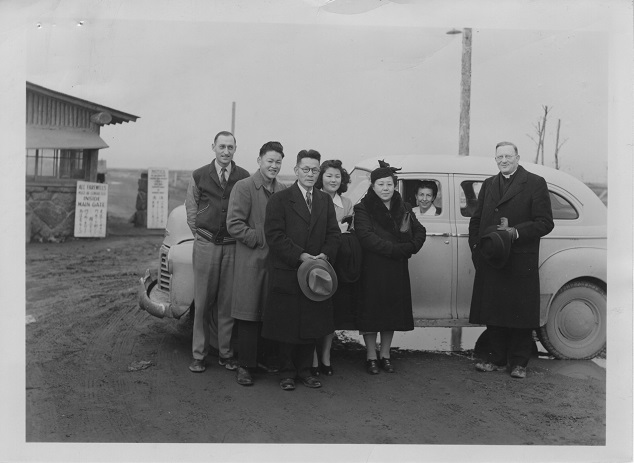 Rev. L.H. Tibesar posing with the Kinoshita family at gates of Camp Minidoka, Idaho in 1945. VR700.02282