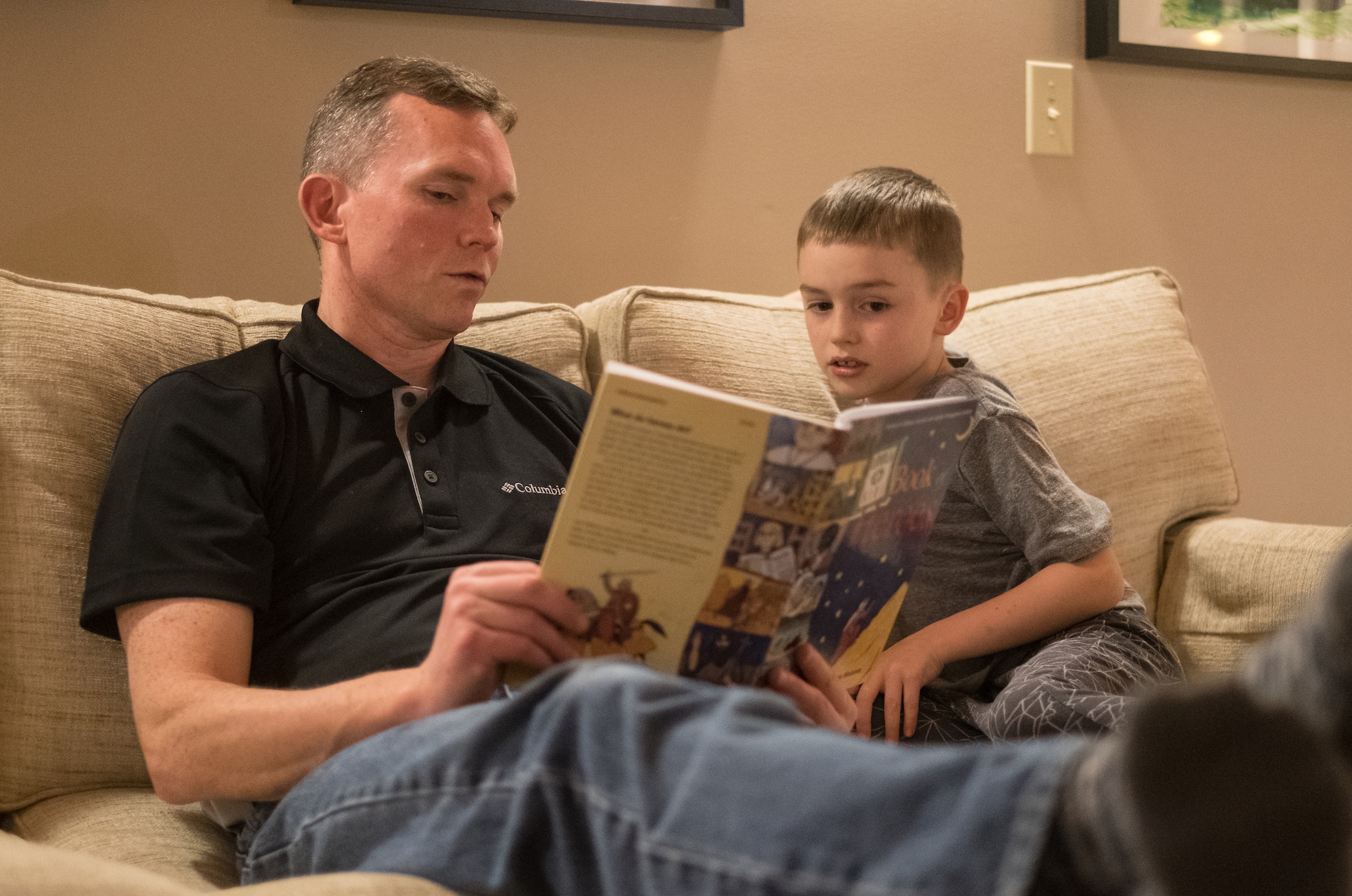 Keith Mack, left, reads from a book about saints to son Patrick before bedtime at their home on Saturday January 21, 2017 in Oak Harbor, Washington. (PHOTO by Stephen Brashear) Domestic Church, father, son, reading, book.