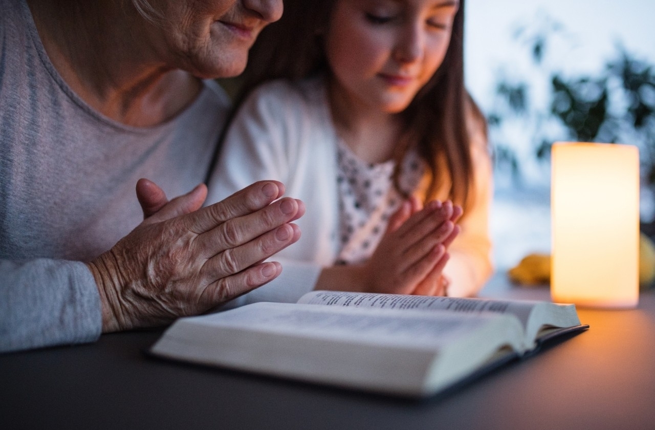 Grandmother and child praying with Bible