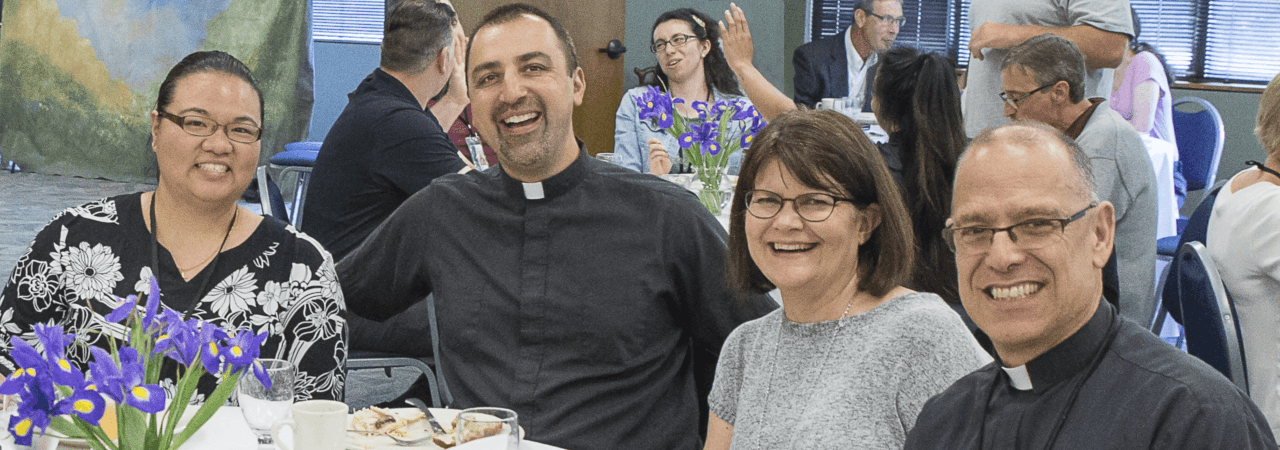 women with priests sitting at a table