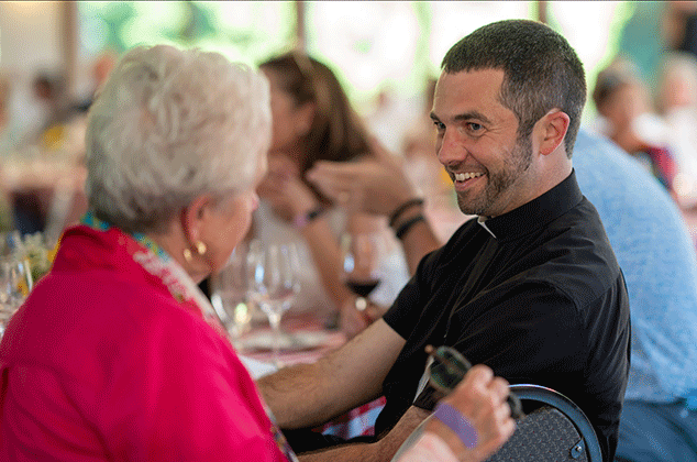 Father Justin Ryan talking to a woman at the 2025 BBQ