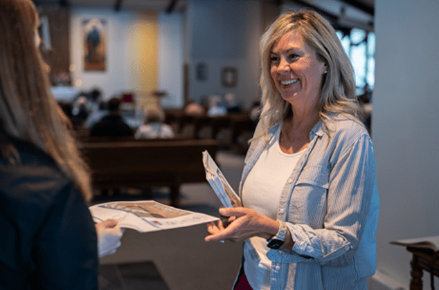 a woman handing out mass programs